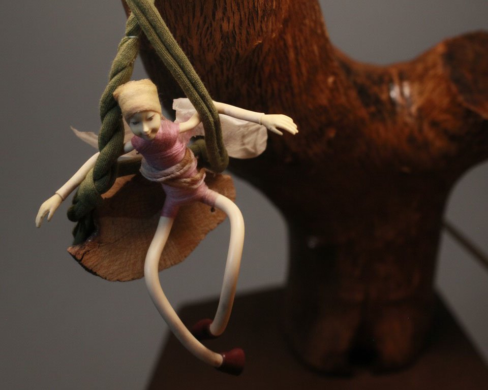 Lámpara decorativa con figura de elfo y estructura de rama natural.